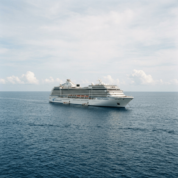 Large white cruise ship named Mare Splendid floating on calm open sea with a blue sky and scattered clouds